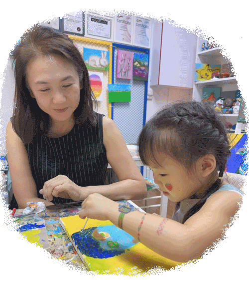 Elfin Ng guiding a young artist through a painting at stART Studio