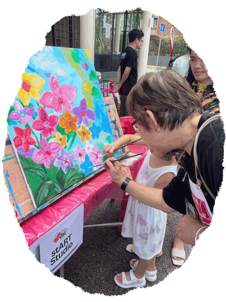 A little artist adds her brushstrokes to a flower canvas at a stART Studio family art jam
