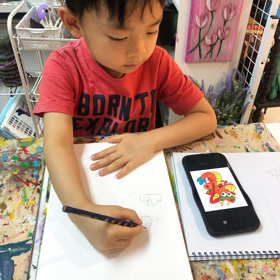 A young artist sketching from a reference before adding colour