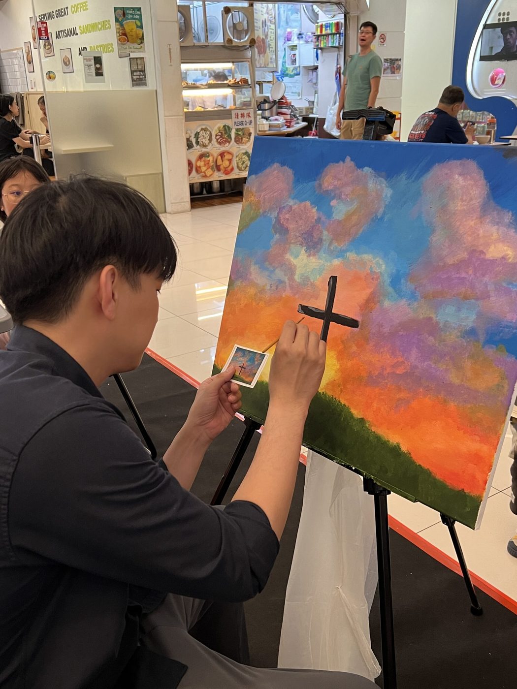 A student reworking a sunset canvas on the easel
